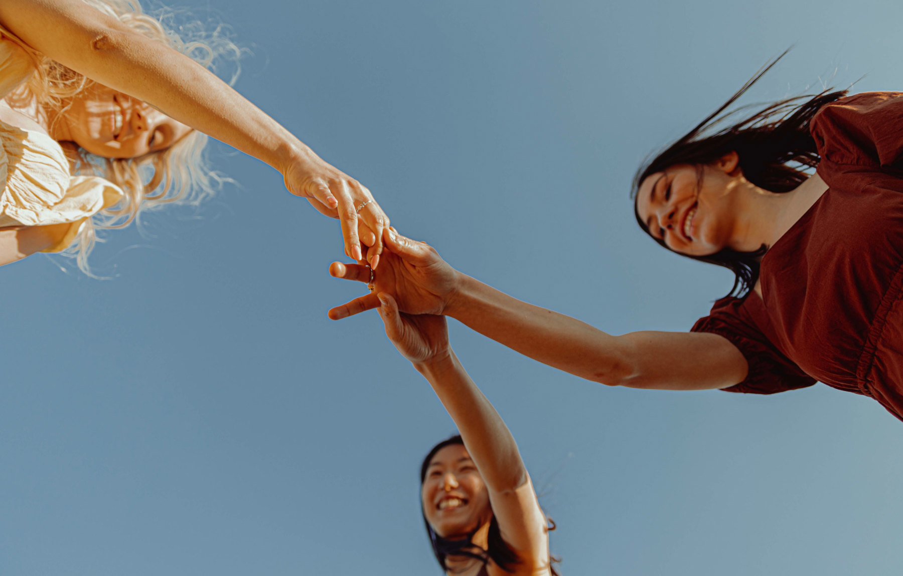 Tre damer holder hender